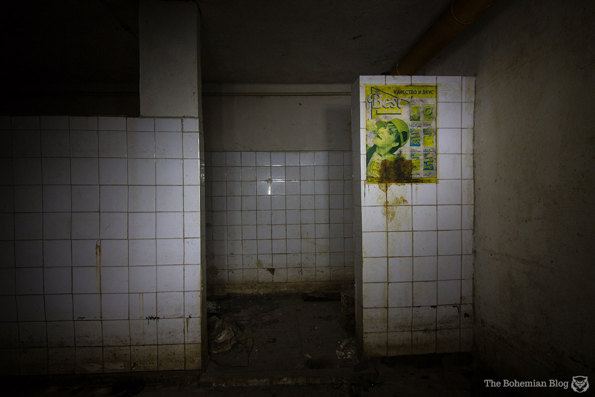 A single poster hangs in the washroom of an abandoned bomb shelter.