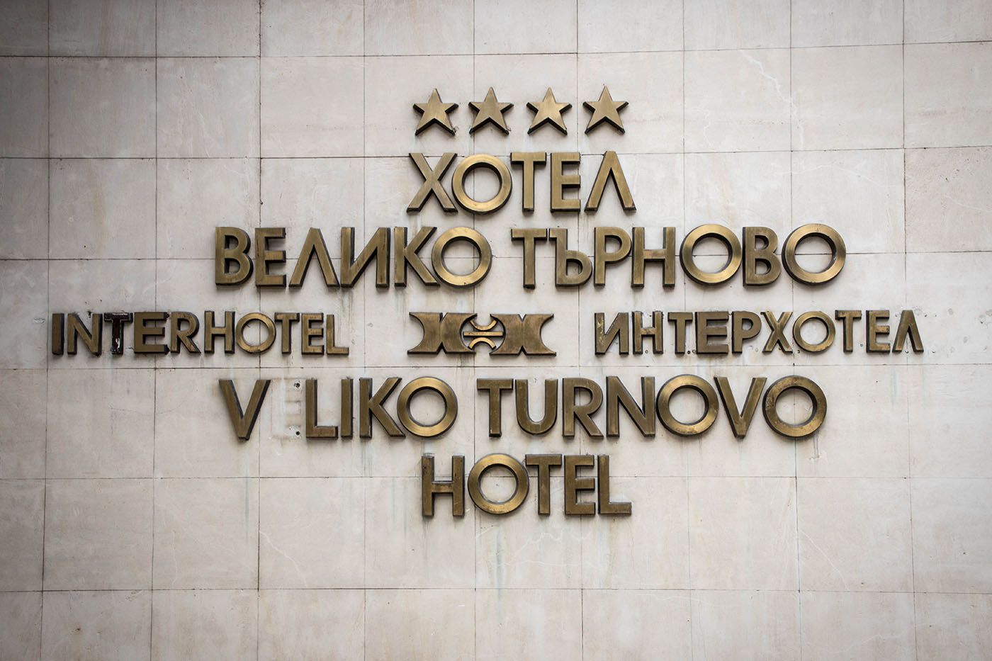 Signage on the marble wall beside the entrance to Interhotel Veliko Turnovo. Pictured after the hotel's closure, in September 2022.